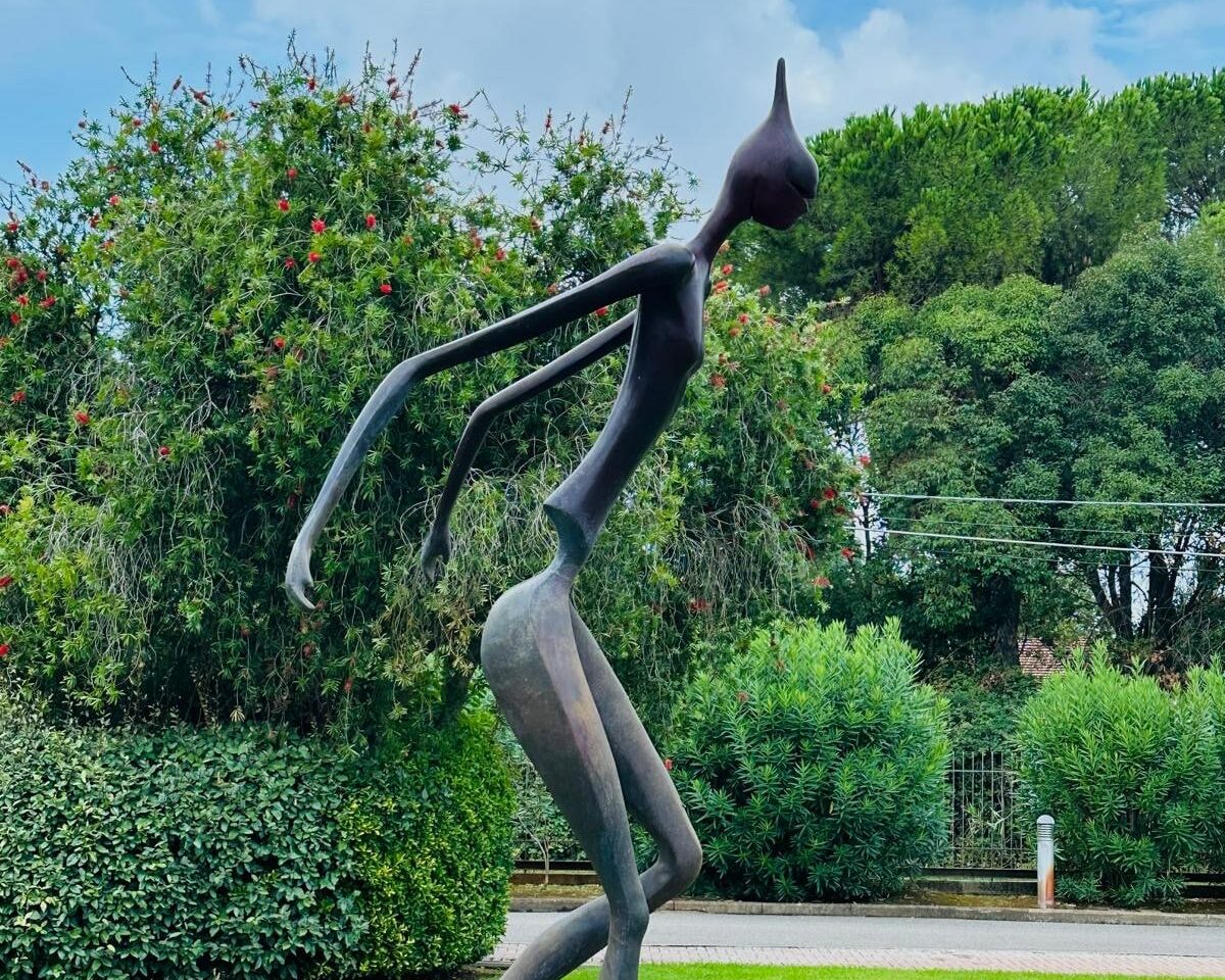 Nella foto c'è un prato verde con una statua in bronzo di forma simil umana che mima la corsa.